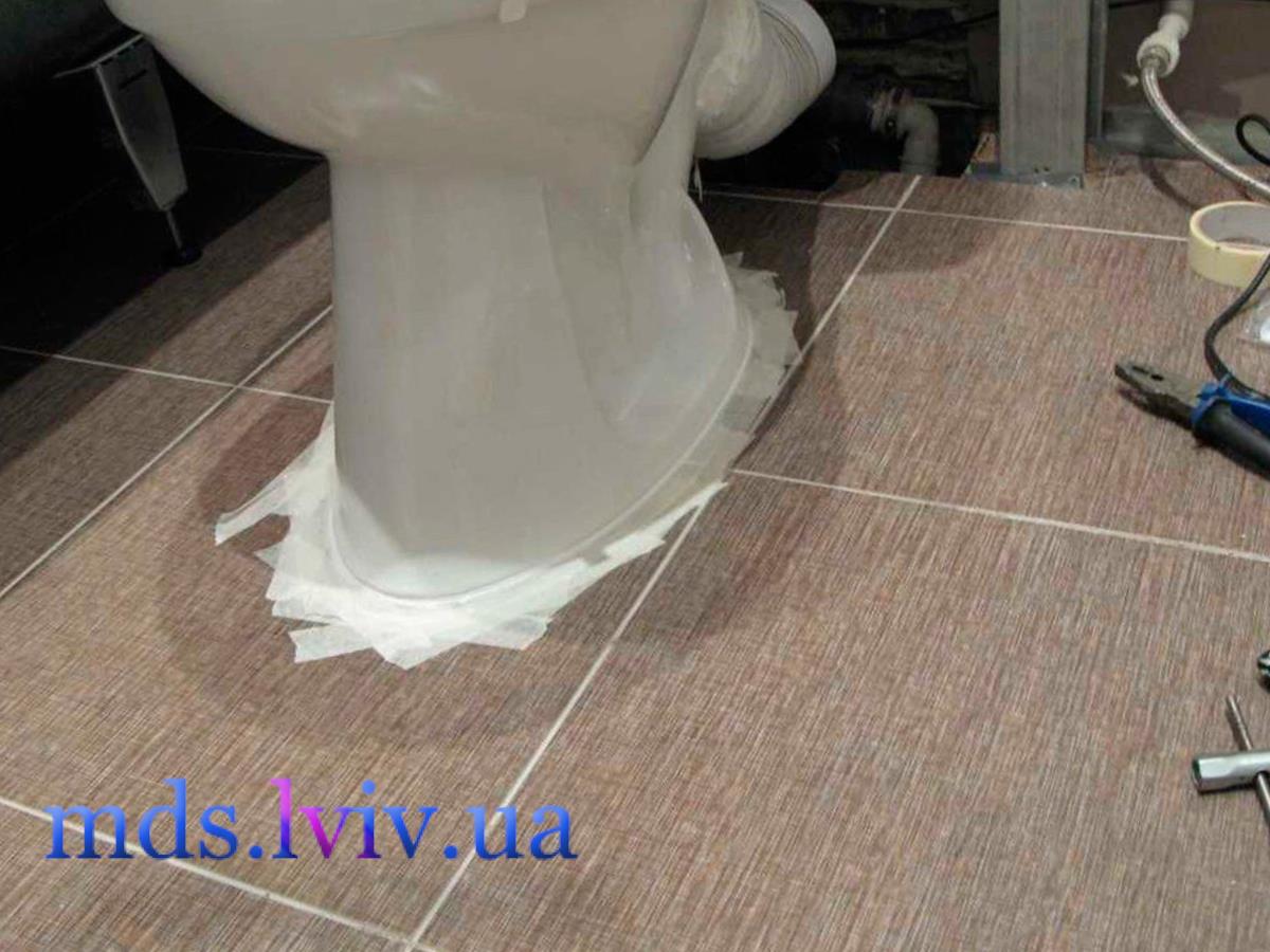 майстер сантехнік встановлює унітаз